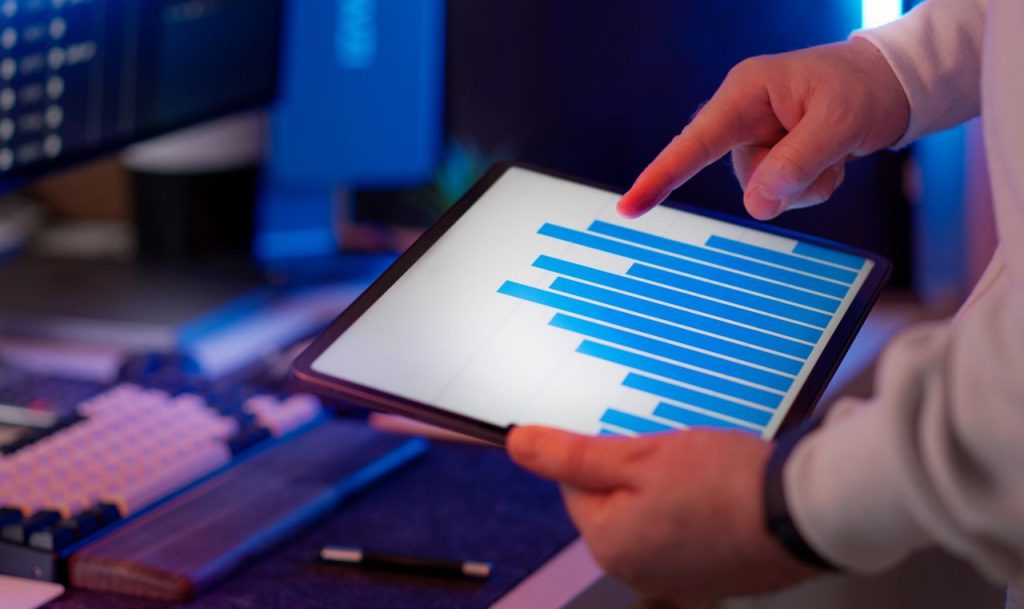 who-we-are Business professional analyzing bar chart on tablet in office setting, highlighting data insights.